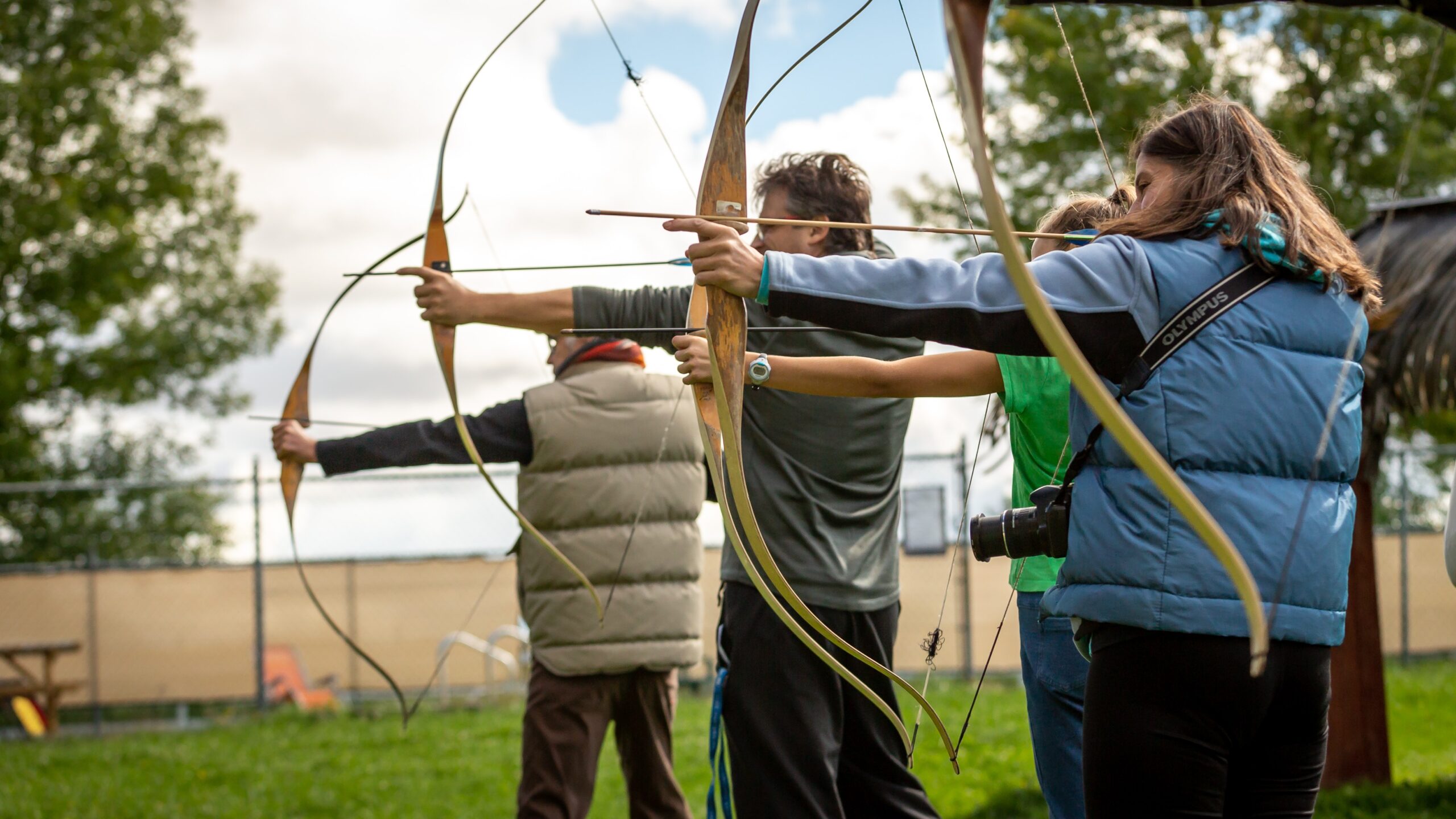 Group participating in archery activity outdoors, focusing on teamwork and communication skills, relevant to equine-assisted learning and team-building strategies.